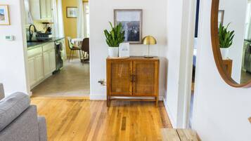 A modern living room with hardwood flooring, a grey sofa, a wooden side table, and a mirror.