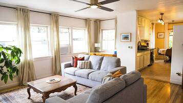 A living room with a grey sofa, a wooden coffee table, and a ceiling fan.