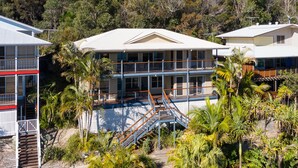 A multi-story building with balconies, surrounded by tropical vegetation. - The Beachaus - Spacious Beachfront Holiday Home (Moreton Island)