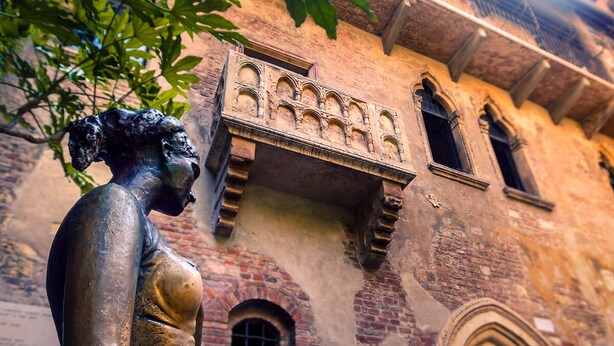 A statue of a woman in front of a historic building with arched windows and a balcony. - [Porta Nuova Suite] 24/7 Self Check-in (Verona)