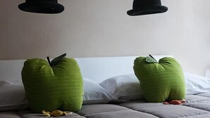 A bed with green pillows and two black hats hanging above it. - [Porta Nuova Suite] 24/7 Self Check-in (Verona)