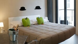 A hotel room with a bed, a small table with a lamp, and two green pillows. - [Porta Nuova Suite] 24/7 Self Check-in (Verona)