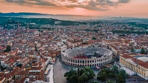 A cityscape with a prominent circular building, likely a historical site, surrounded by densely packed buildings and a clear sky. - [Porta Nuova Suite] 24/7 Self Check-in (Verona)