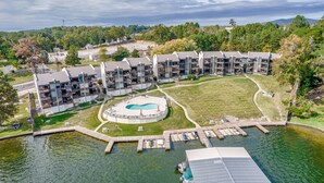 A modern apartment complex with a central swimming pool, docked boats, and a surrounding grassy area. - Exquisite Lakefront Condo - Pool - Boat Slip (Hot Springs)