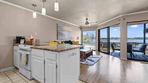 A kitchen with white cabinets, a granite countertop, and a built-in oven. There is a dining area with a table and chairs, and a large window offering a view of the outdoors. - Exquisite Lakefront Condo - Pool - Boat Slip (Hot Springs)