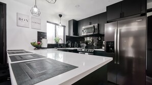 Une cuisine moderne dotée d’un grand îlot central, d’appareils électroménagers en acier inoxydable et de meubles de cuisine noirs.