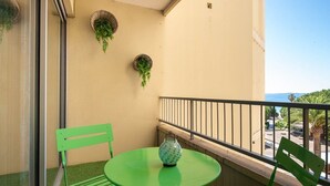 A balcony with a green table and chairs, a hanging plant, and a view of the sea. - Ref: SUP115: 2-room apartment in beachfront residence in Le Lavandou 4 pers (LE LAVANDOU)