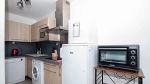 A compact kitchen with wooden cabinets, a white washing machine, a white refrigerator, and a black toaster oven. - Ref: SUP115: 2-room apartment in beachfront residence in Le Lavandou 4 pers (LE LAVANDOU)