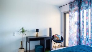 A bedroom with a bed, a desk, a chair, a potted plant, and a window with curtains. - Ref: SUP115: 2-room apartment in beachfront residence in Le Lavandou 4 pers (LE LAVANDOU)