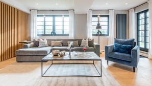 A modern living room with a grey sofa, a blue armchair, and a coffee table with decorative items. - Modern. Gemütlich. Zentral. - Objekt-id: Ilw/04 - Inselliebe Westerland (Sylt)