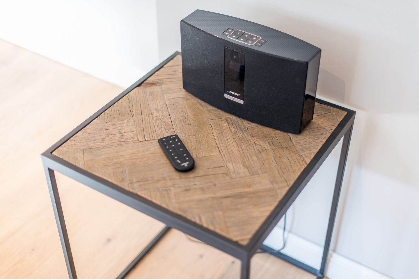 Un diffusore nero su un tavolo di legno, con un telecomando accanto.