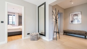 A modern bedroom with a bed, a large mirror, a bench, and a floor lamp.