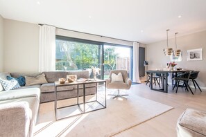 A modern living room with a sofa, armchair, coffee table, and dining area with chairs and a table. - Modern. Gemütlich. Zentral. - Objekt-id: Ilw/01 - Inselliebe Westerland (Sylt)