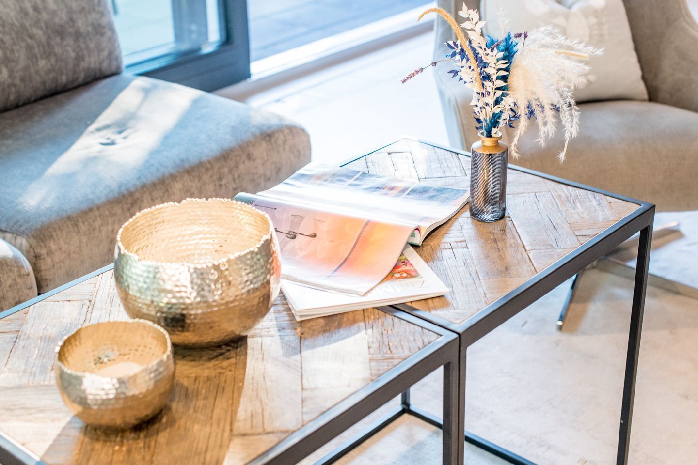 A modern living room with a glass coffee table, a magazine, and decorative items.