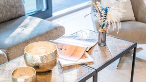 A modern living room with a glass coffee table, a magazine, and decorative items.