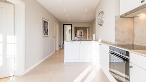 A modern kitchen with white cabinetry, a built-in oven, and a stainless steel range hood.