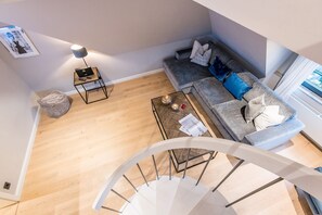 Un salon moderne avec un canapé gris, une petite table basse et un escalier en colimaçon.