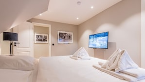 Une chambre d’hôtel avec deux lits, un téléviseur à écran plat et une porte donnant sur une autre pièce.
