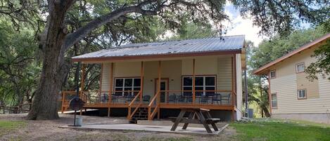 A rustic cabin with a porch, wooden deck, and a picnic table.