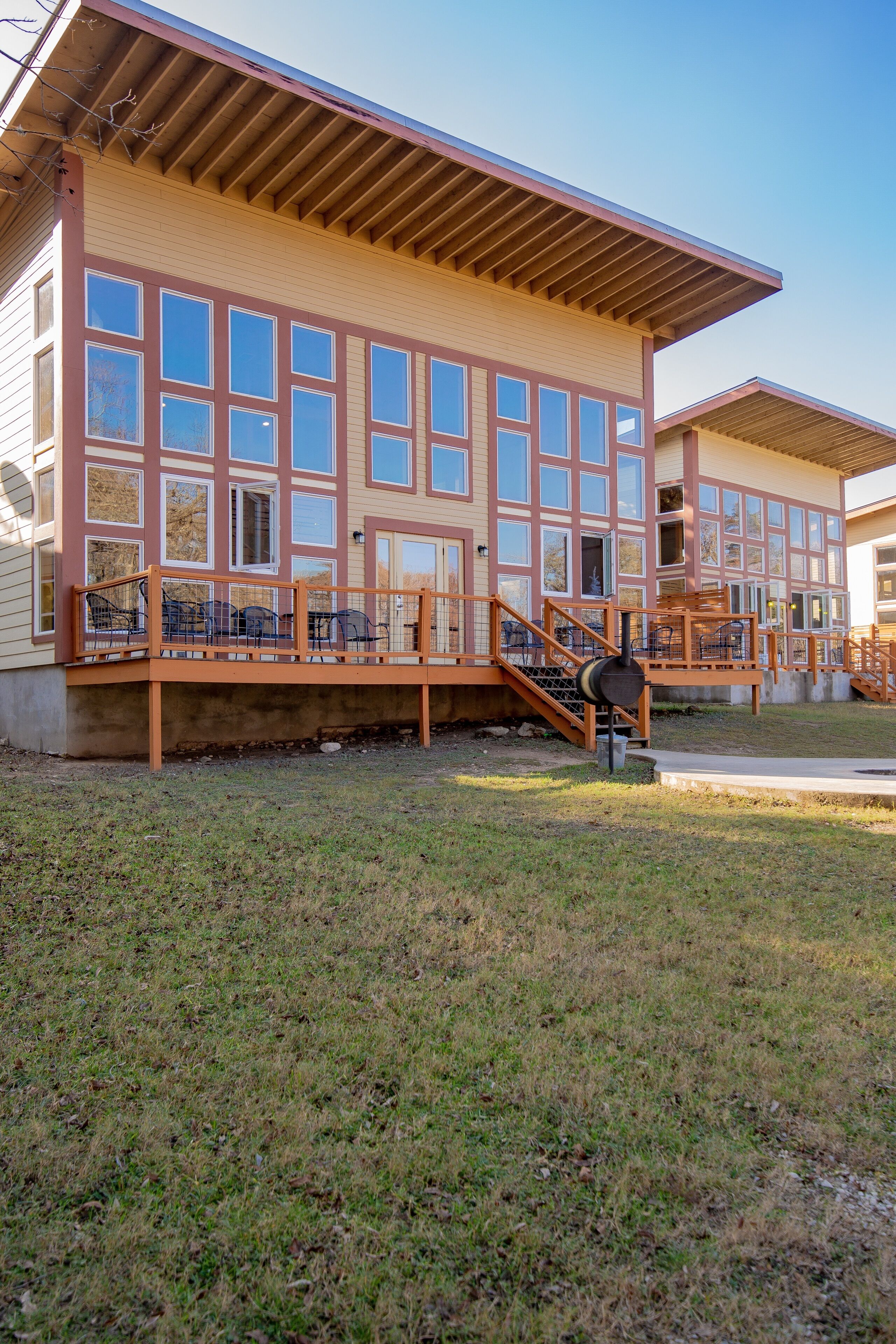 A building with multiple windows, a covered deck, and a staircase leading to the entrance.