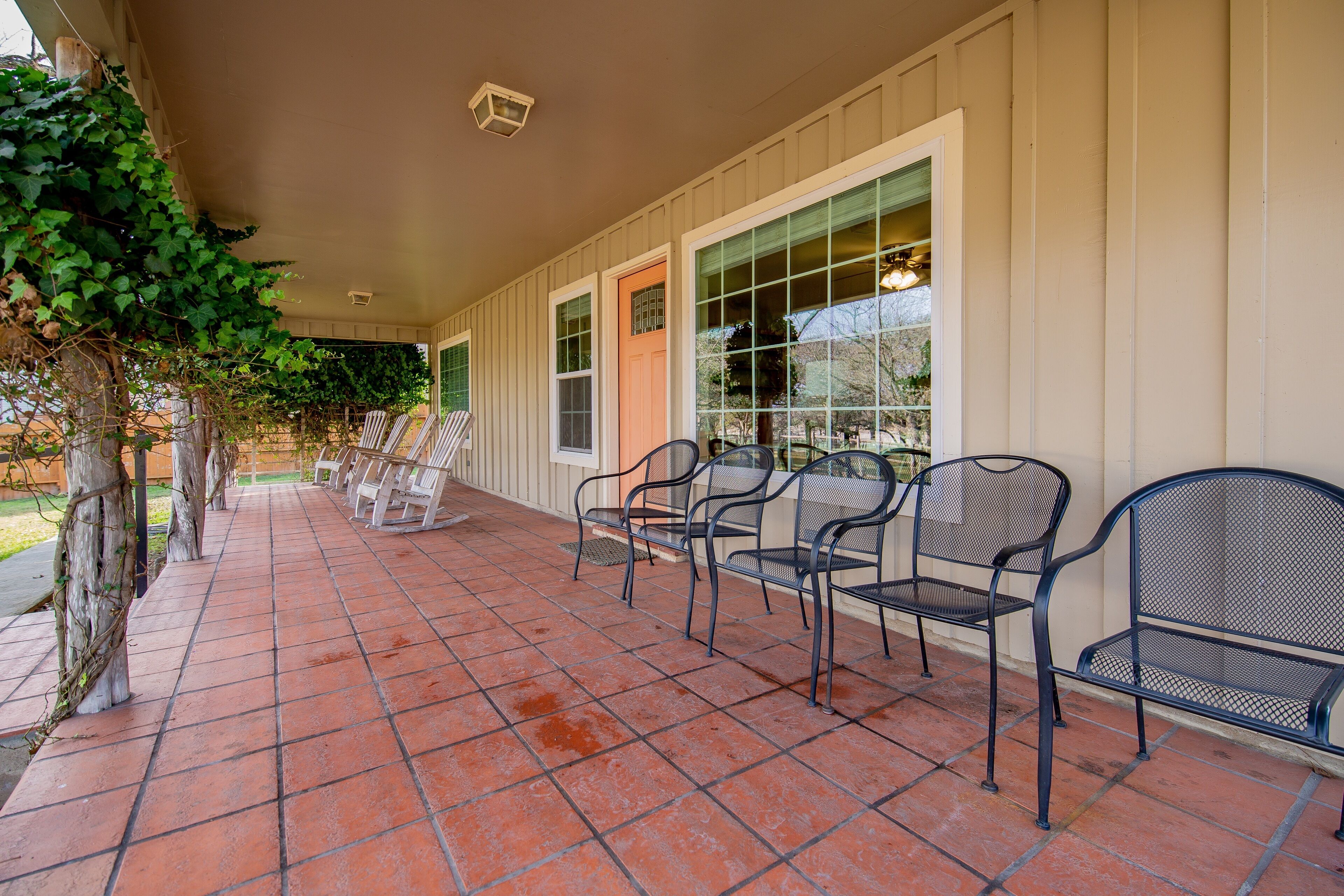 A covered patio with tiled flooring and metal chairs.