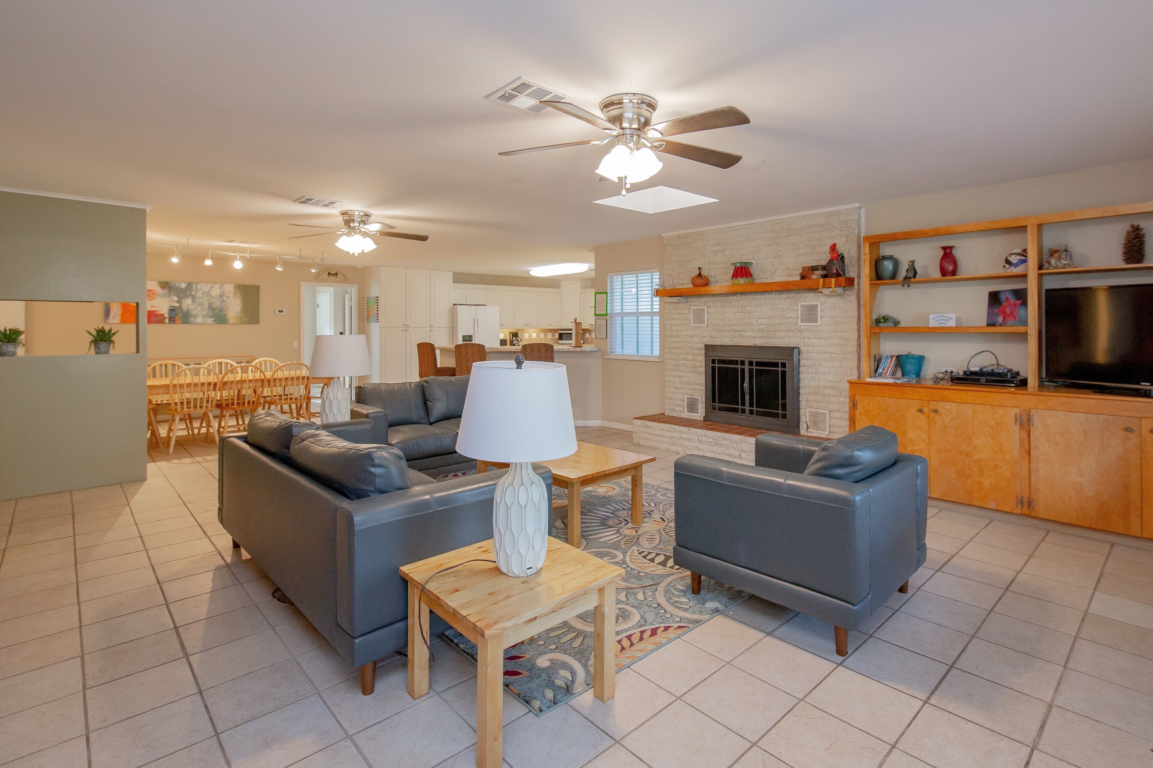 A spacious living room with a grey sofa, a wooden coffee table, and a ceiling fan.