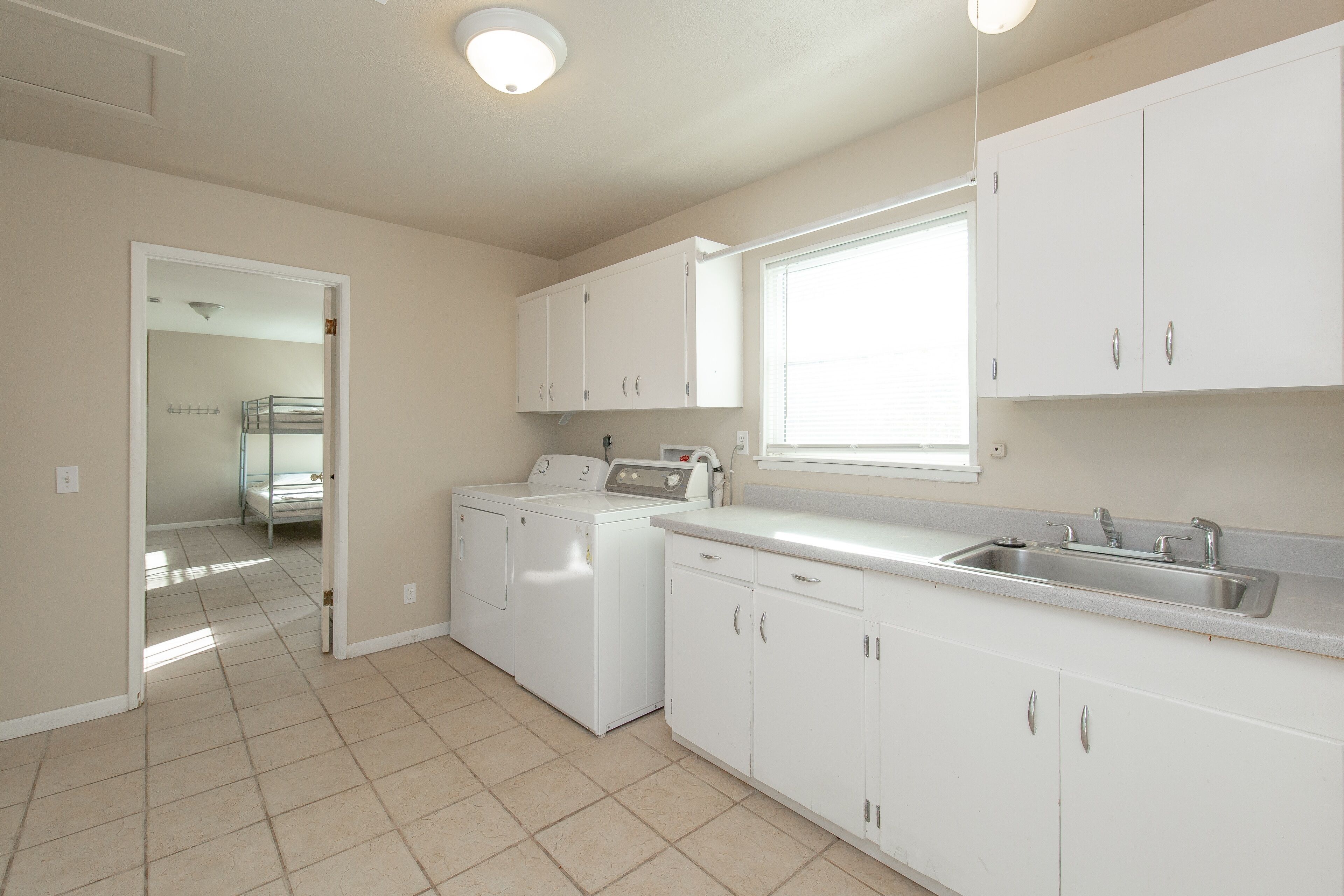 A laundry room with a washing machine and dryer, a sink, and cabinets.