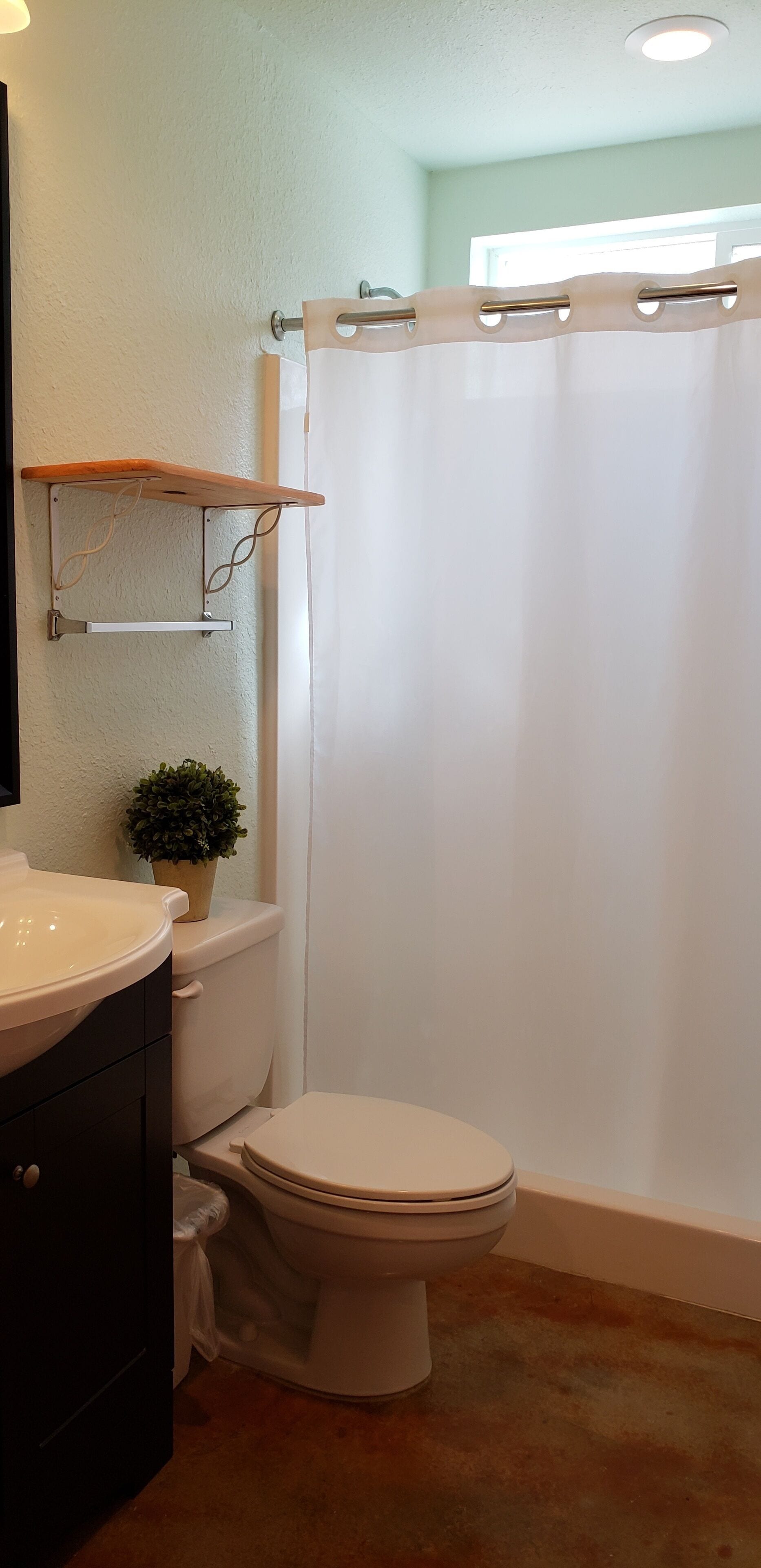 Un baño con inodoro, lavabo, una pequeña planta en maceta y cortina de ducha.