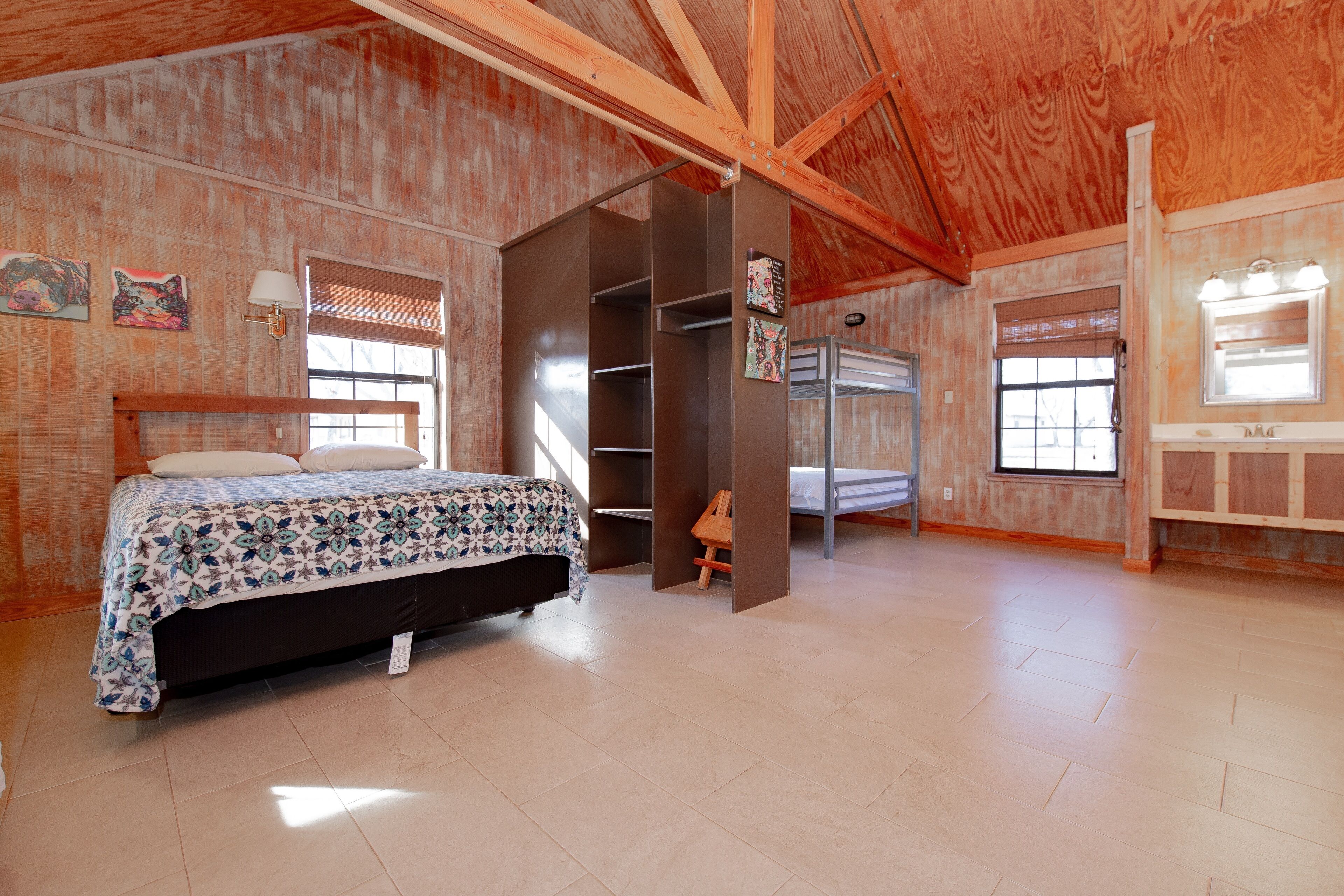 Een ruime slaapkamer met een groot bed, inbouwkasten en een raam met zonwering.