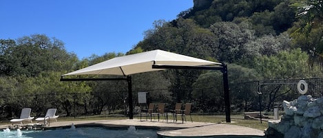 Una piscina al aire libre, sombrillas, sillones reclinables de piscina