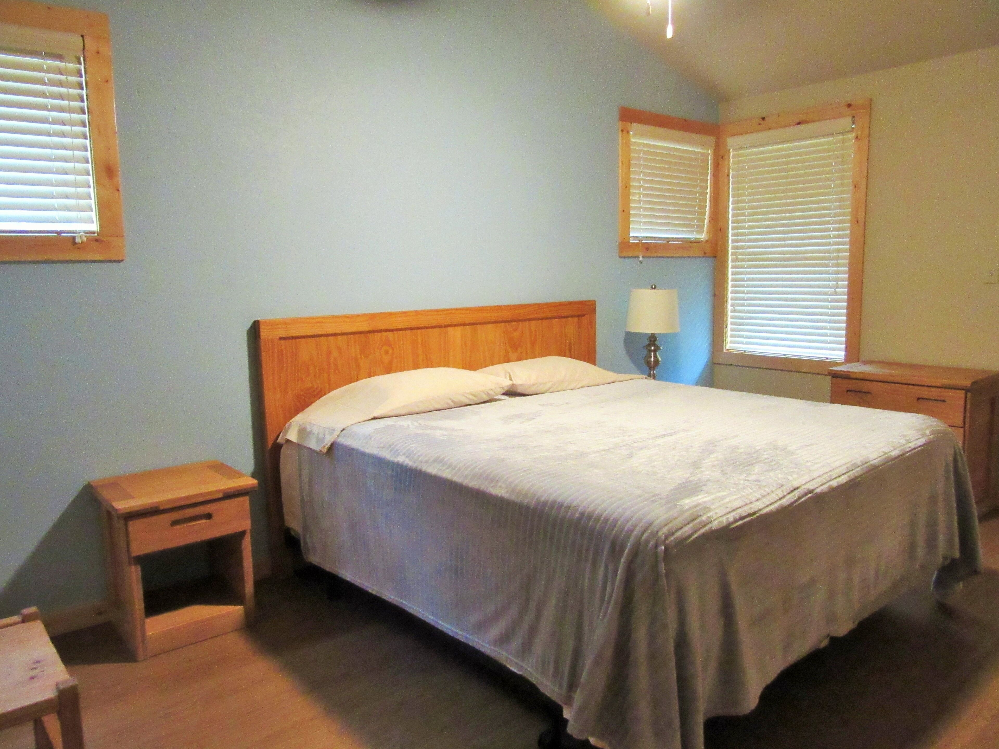 A bedroom with a single bed, two bedside tables, a nightstand, and a lamp.