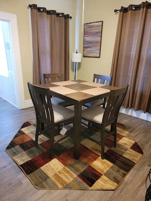 Cozy dining area with a wooden table and chairs, area rug, and a floor lamp.