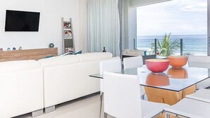 Ett modernt vardagsrum med en vit soffa, ett glasbord och två röda skålar, samt en takfläkt.