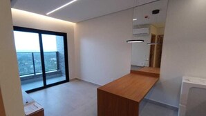 A modern, minimalist room with a large window, a wooden desk, and a washing machine.