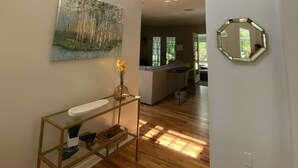 Un intérieur spacieux avec un plafond haut, un plancher en bois, un escalier menant à un niveau supérieur, une cuisine moderne et un coin repas.