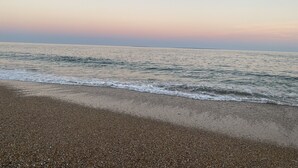 Une plage de galets, avec des vagues, au coucher du soleil.