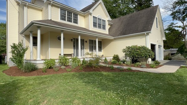A two-story house with a front porch, columns, and a well-maintained lawn.