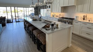 A spacious kitchen with a large island, white cabinetry, and a chandelier. - Luxury Waterfront Home (Coronado)