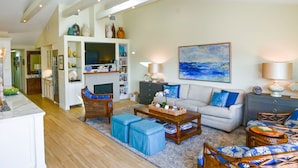 A spacious living room with a fireplace, a television, and a large painting. - Luxury Waterfront Home (Coronado)