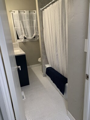 A bathroom with a toilet, sink, and shower area. - Our little Gem, remodeled and new everything. Close to down town. (Emmett)