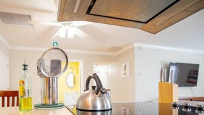 Une cuisine moderne équipée d’une bouilloire, d’une bouteille et d’un ventilateur de plafond.