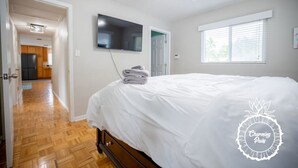 Une chambre dotée d’un grand lit, d’un téléviseur à écran plat fixé au mur et d’une fenêtre avec des stores.