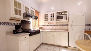 Una cucina con mobili bianchi, un fornello, un forno a microonde e un lavandino.