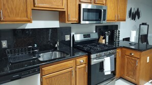 Eine moderne Küche mit Holzschränken, einer Edelstahl-Mikrowelle, einem Gasherd und einem eingebauten Backofen.