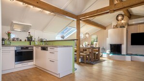 A modern kitchen with white cabinets, a built-in oven, and a dining area with a wooden table and chairs.