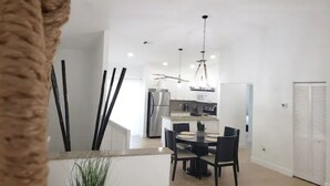 A modern kitchen with stainless steel appliances, a dining area with a round table and chairs, and a white interior. - Bimini Dreams, Steps from the Beach, optional Golf Cart rent (Bailey Town)