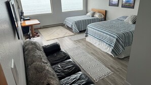 Ein Schlafzimmer mit zwei Betten, einem Schreibtisch und Blick ins Freie.