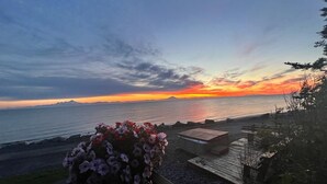 Sonnenuntergangsblick von einer Terrasse mit Blick auf einen Strand, inklusive Holzgeländer und Blumenarrangement.