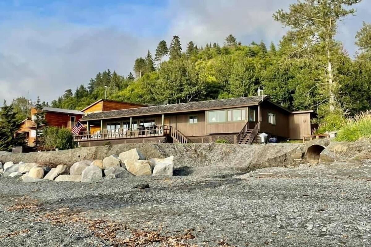 A cabin with a deck, large windows, and a stone wall.