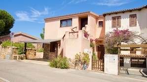 A two-story building with a stone facade, a covered entrance, and a gated driveway. - Erica Piano Terra 150m From the Beach, Golfo Aranci, Italy (Golfo Aranci)